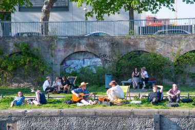 İnsanlar gitarını oynayan bir adam ile Spree Nehri kıyısında asılı