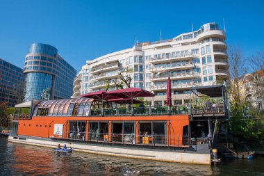Arka planda daire binası ile Spree Nehri üzerinde bir mavna üzerinde Restoran