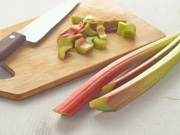 Cooking process. Preparing rhubarb cake. Rhubarb stems arranged on old wooden background, whole and cut on pieces. Selective focus on the front.