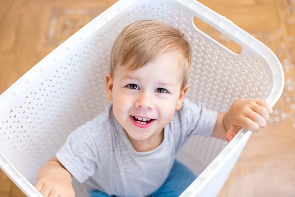 Двухлетний мальчик сидит в корзине для белья — стоковое фото