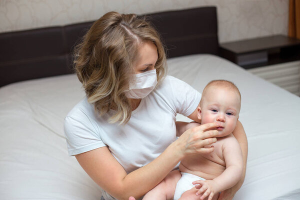 Мать держит своего больного мальчика в медицинской маске
