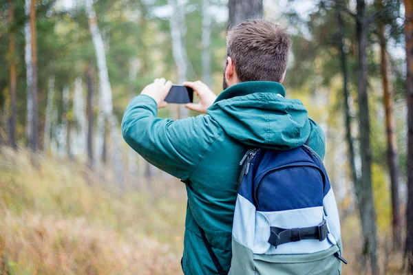 Erkek uzun yürüyüşe çıkan kimse ile onun smartphone bir ormandaki fotoğraf çekme