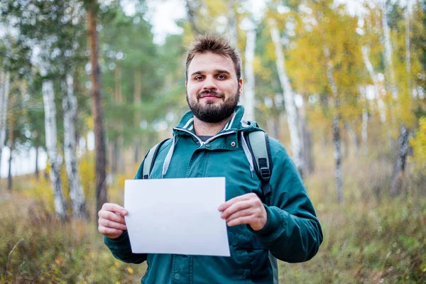 Your text here. male hiker is holding a white paper where you can insert your text