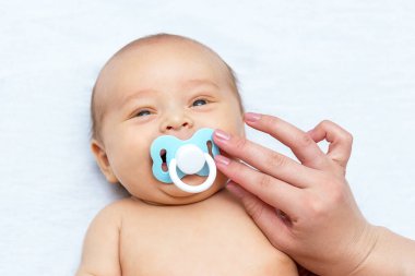 Yeni doğan oğluna bir emzik veren anne el