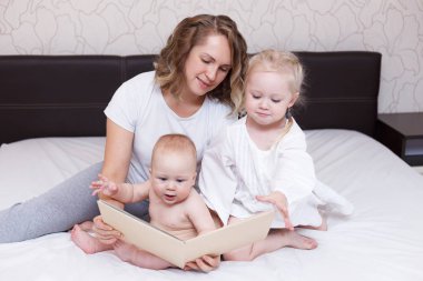 Anne evde iki çocuklarıyla birlikte bir yatak üzerinde oynama