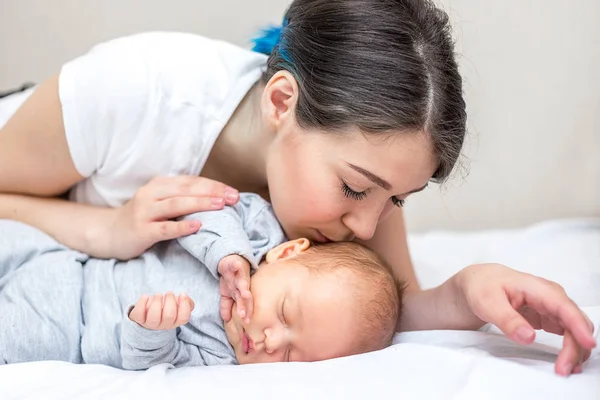 Genç mutlu anne yeni doğan oğlunu öpüyor