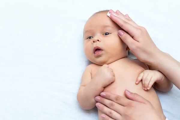 母が綿パッドで彼女の生まれたばかりの息子の顔を洗浄します — ストック写真