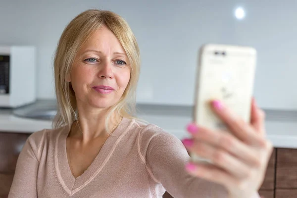 bir akıllı telefon ile evde bir selfie alarak orta yaş kadın