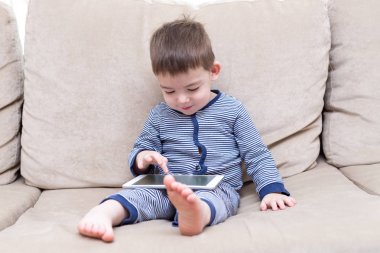 yürümeye başlayan çocuk evde bir kanepede tablet kullanma