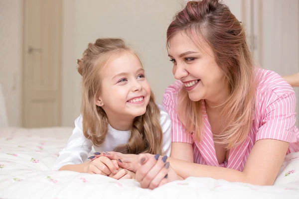 Mother and daughter playing on a bed together at home