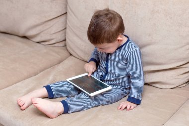 yürümeye başlayan çocuk evde bir kanepede tablet kullanma