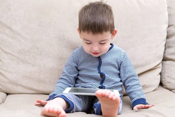 yürümeye başlayan çocuk evde bir kanepede tablet kullanma