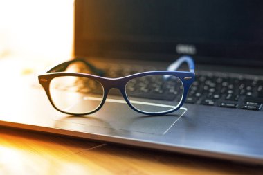 ahşap bir masa üstünde a laptop yatarken gözlük