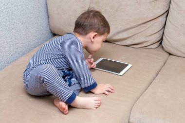 yürümeye başlayan çocuk evde bir kanepede tablet kullanma