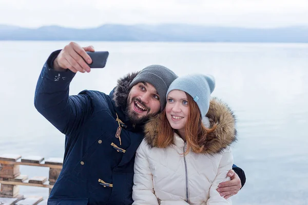 Bir kış gölde bir selfie alarak yürüyüşçü birkaç gülümseyen genç