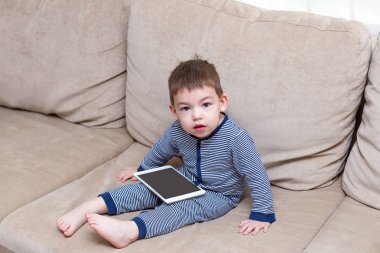 yürümeye başlayan çocuk evde bir kanepede tablet kullanma