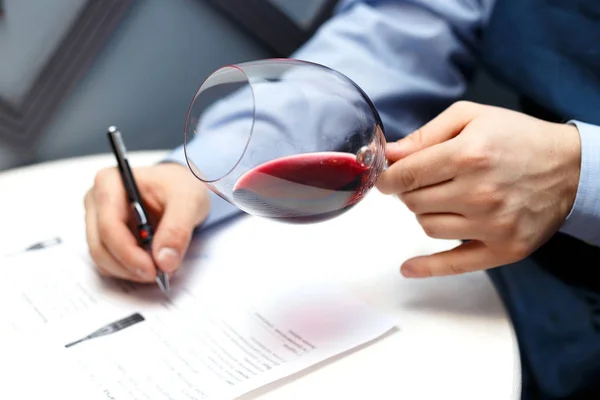 male sommelier is checking and testing red wine and making notes