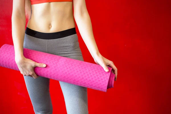 Uygun kadın bir spor salonunda bir yoga mat tutuyor