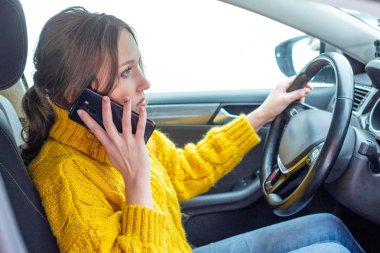 Kadın araba kullanırken telefonla konuşuyor.
