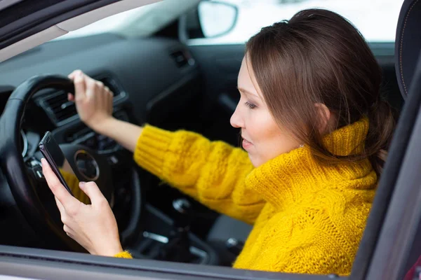 Text and drive woman. A woman is texting on her phone while driving