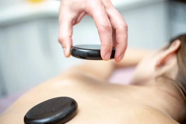 Una donna sta ricevendo un massaggio di pietra calda in una spa — Foto Stock