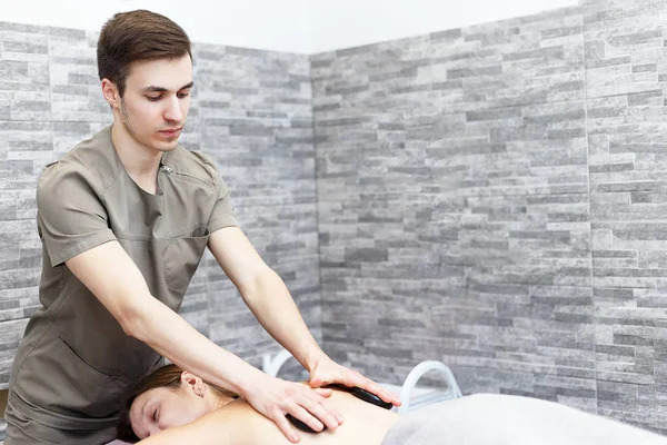 Una donna sta ricevendo un massaggio di pietra calda in una spa — Foto Stock