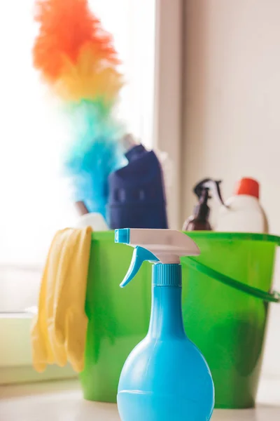 Plastic green bucket with cleaning supplies on window. Equipment for house cleaning