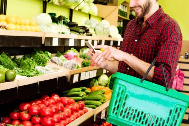 Beyaz adam kırmızı kareli gömlekli bakkal içinde sebze seçme