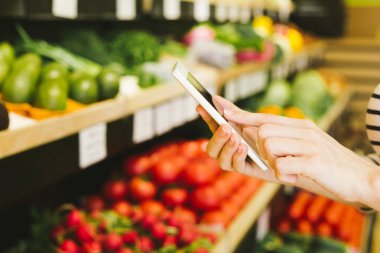 süpermarket ürünleri satın alma sırasında akıllı telefon kullanan kadın