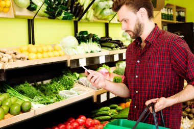 Beyaz delikanlı markette Smartphone kullanarak