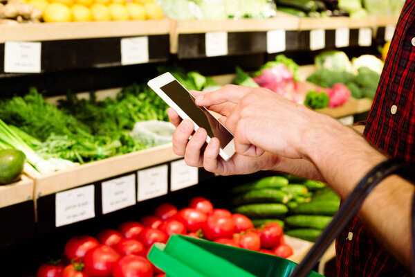 Mans hands using smartphone in grocery store