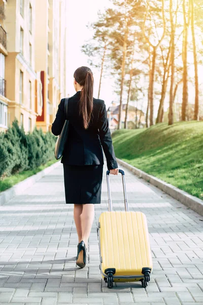 黄色スーツケース屋外でスーツの若い白人ブルネット実業家 ビジネス旅行のコンセプト — ストック写真