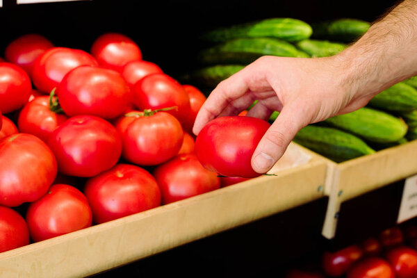 Mans hand choosing tomatoes in grocery