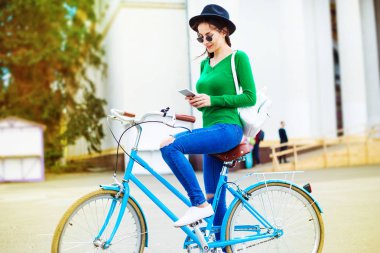 siyah şapka Bisiklet açık sürme sırasında smartphone kullanarak genç kadın