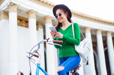 siyah şapka Bisiklet açık sürme sırasında smartphone kullanarak genç kadın