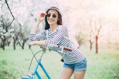 Genç kadın güneş gözlüğü ve şapka ile bisiklet açık poz