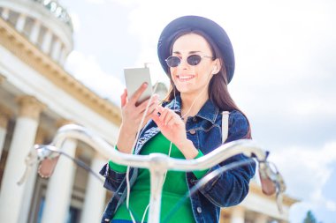 siyah şapka Bisiklet açık sürme sırasında smartphone kullanarak genç kadın