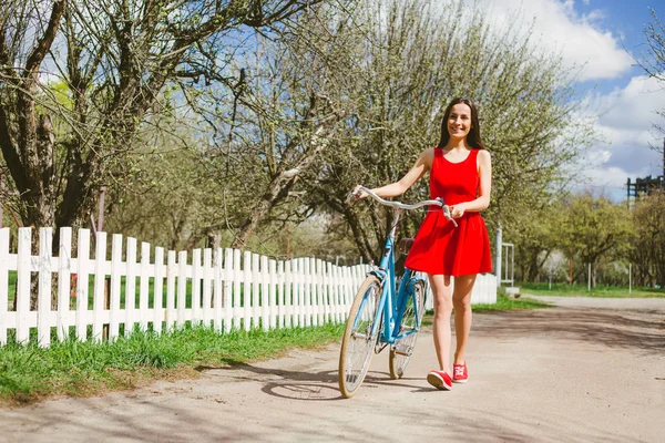 Genç Kadın Açık Kırmızı Elbise Holding Bisiklet Yürüyüş — Stok fotoğraf