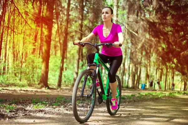 Young caucasian woman riding sport mountain bicycle in forest