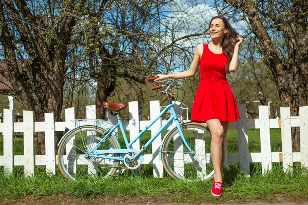 Beyaz Çit Açık Yakınındaki Bisikleti Ile Poz Kırmızı Elbiseli Genç — Stok fotoğraf