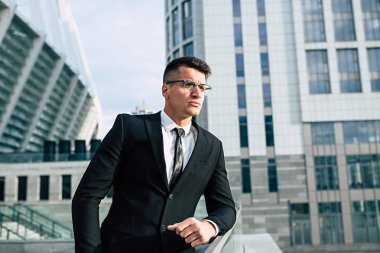 Modern şehir arka plan üzerinde bardaklarda kararlı genç işadamı