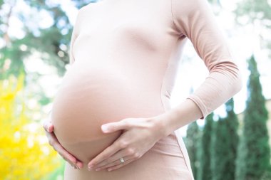 Orta bölüm görünümü bej ince elbise holding göbek Park içinde genç kadın