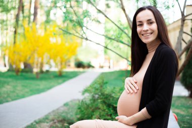 Hamile kadın zevk zaman bankta oturan ve göbek park holding