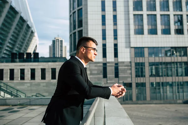 Young businessman in modern city background looking in distance