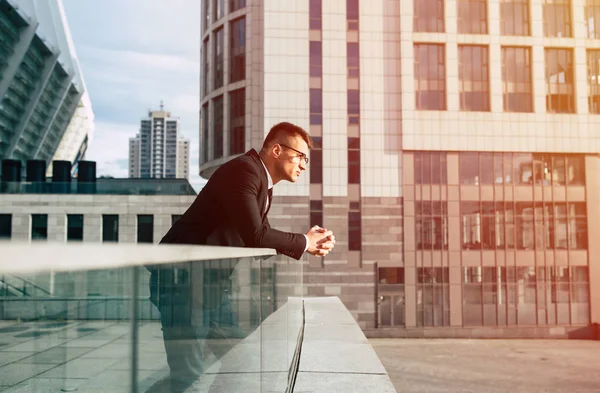 Young businessman in modern city background looking in distance