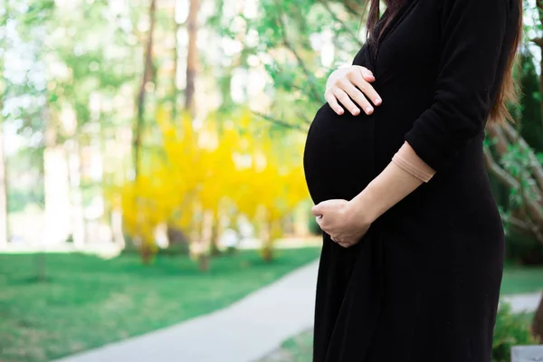 Vista Sección Media Mujer Embarazada Vestido Negro Sosteniendo Vientre Caminando —  Fotos de Stock