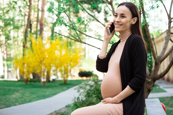 Έγκυος Γυναίκα Που Χαμογελά Κάθεται Στον Πάγκο Μιλάμε Χρησιμοποιώντας Smartphone — Φωτογραφία Αρχείου