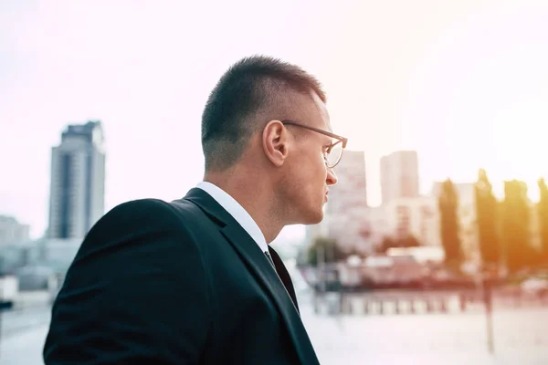 Young businessman in modern city background looking in distance