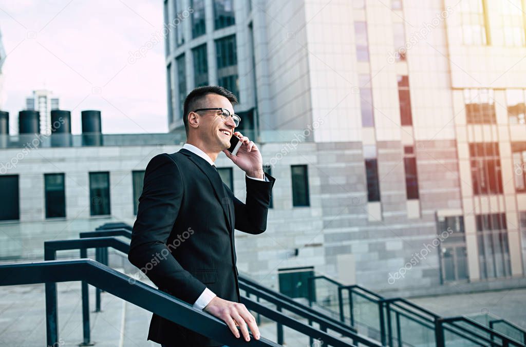 Portrait of young businessman using smartphone on city background