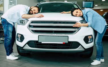 Rahat mutlu genç çift yeni araba sarılma başlık içinde araba konsepti satın alma Bayilik, giymek.